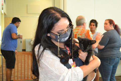 Woman with dark hair holding black kitten