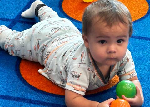 Baby playing with toys on his tummy.