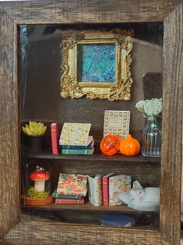 Wooden shadow box with miniature books, art, and decor