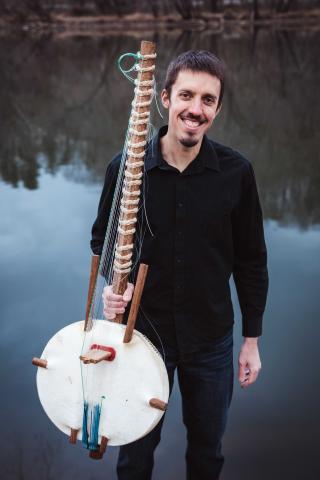 Sean Gaskell standing holding a kora (musical instrument)