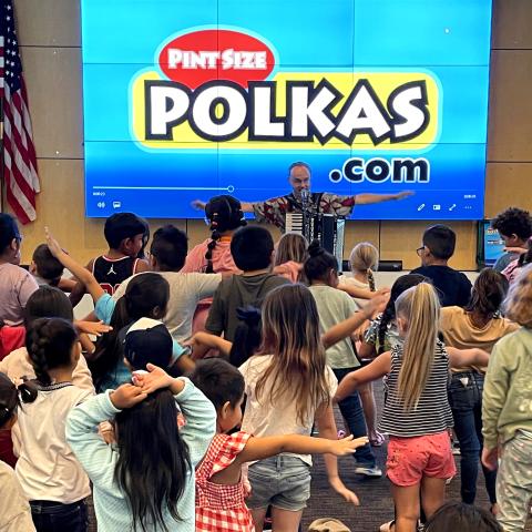 man with accordian leading kids in a dance