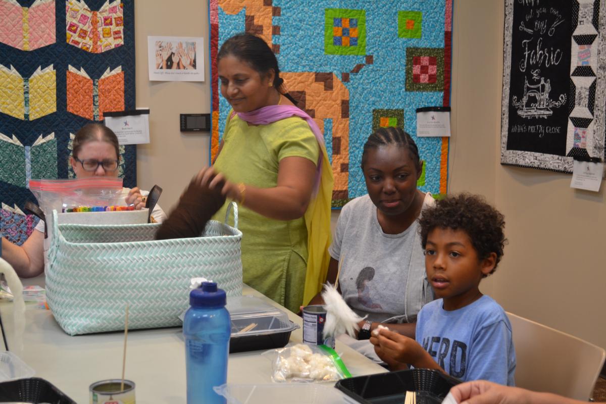 Several people gathered around a table working on fiber arts projects